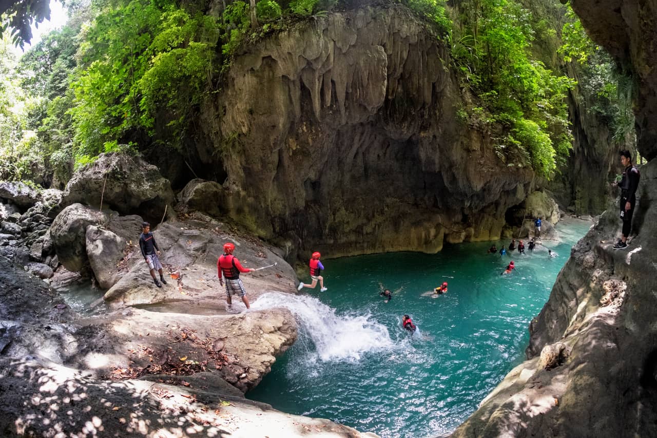 Canyoneers jumping into a turquoise pool on the Kanlaob River, Alegria